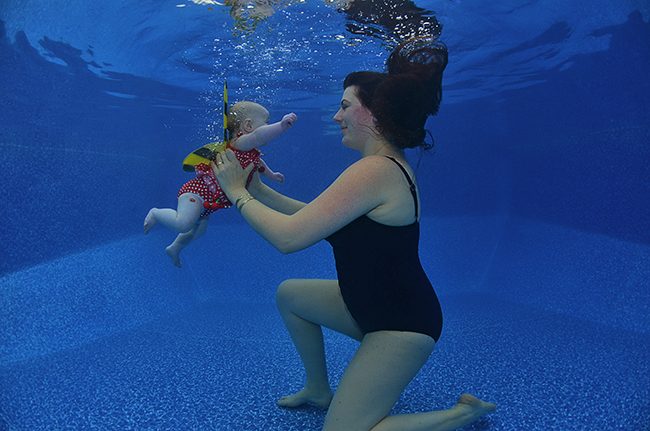 Mother holding her baby underwater during a gentle first-water session in Barcelona.