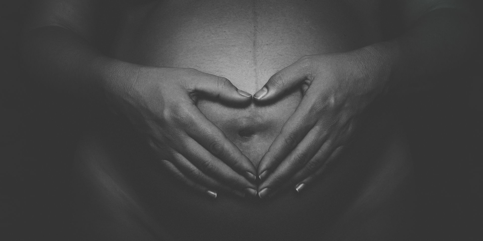 Maternity portrait, hands cradling the bump — underwater maternity in Barcelona.