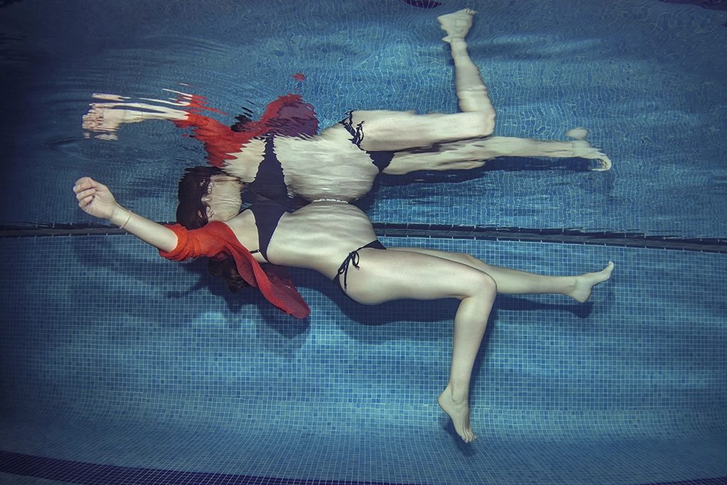 Underwater maternity portrait, a red scarf trailing through the water, Barcelona.